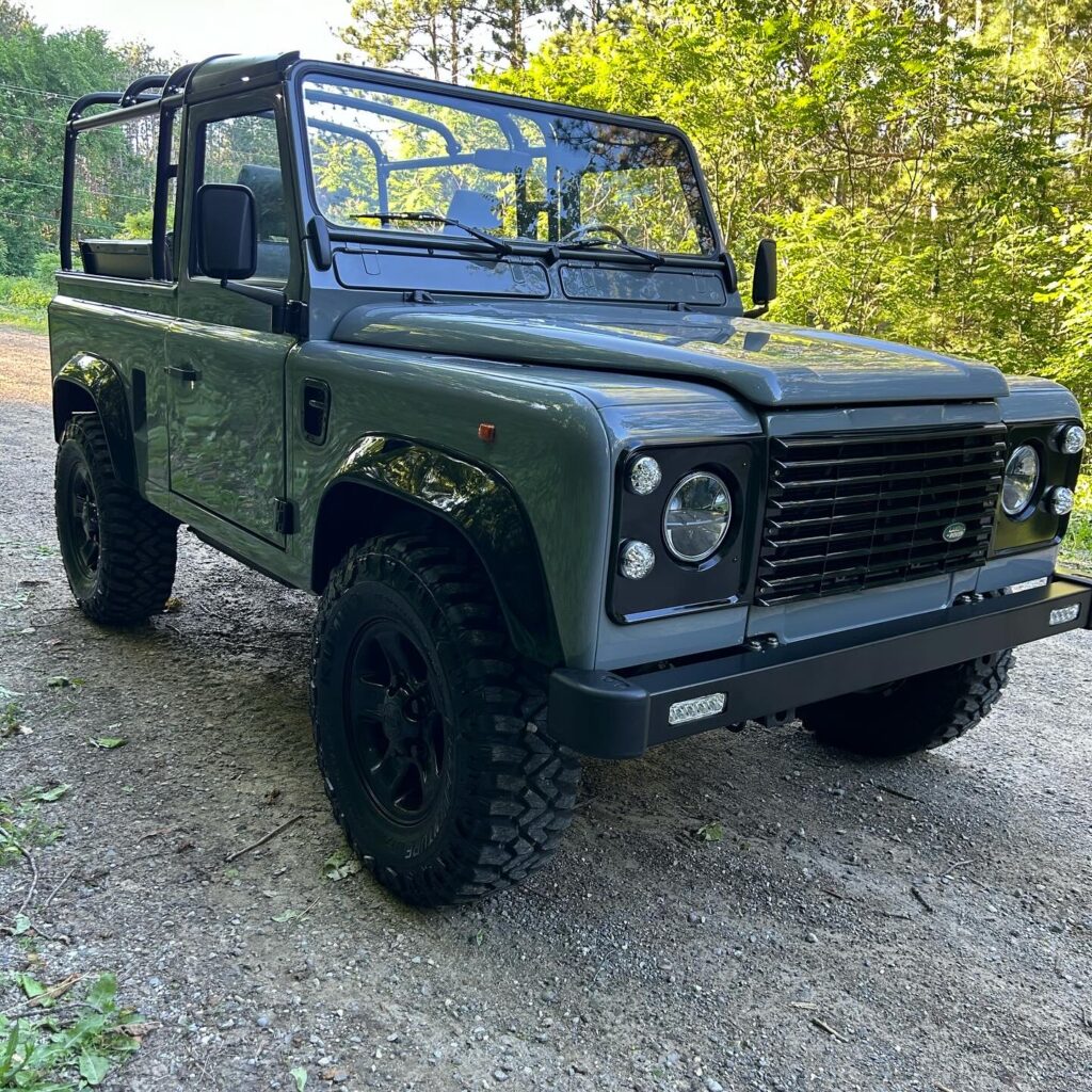 Front three-quarter view of The Nazaré, a Dolphin Grey Defender 90 soft top, on a gravel road