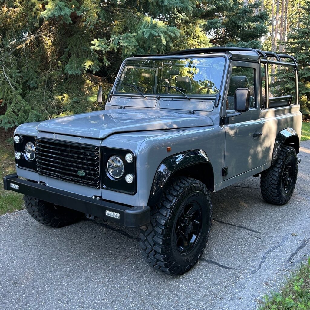 Front three-quarter view of The Nazaré, a Dolphin Grey Defender 90 with roll bars, on a driveway