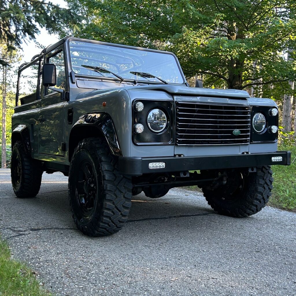 Low front view of The Nazaré, a Dolphin Grey Defender 90 300Tdi with gloss black Boost alloys