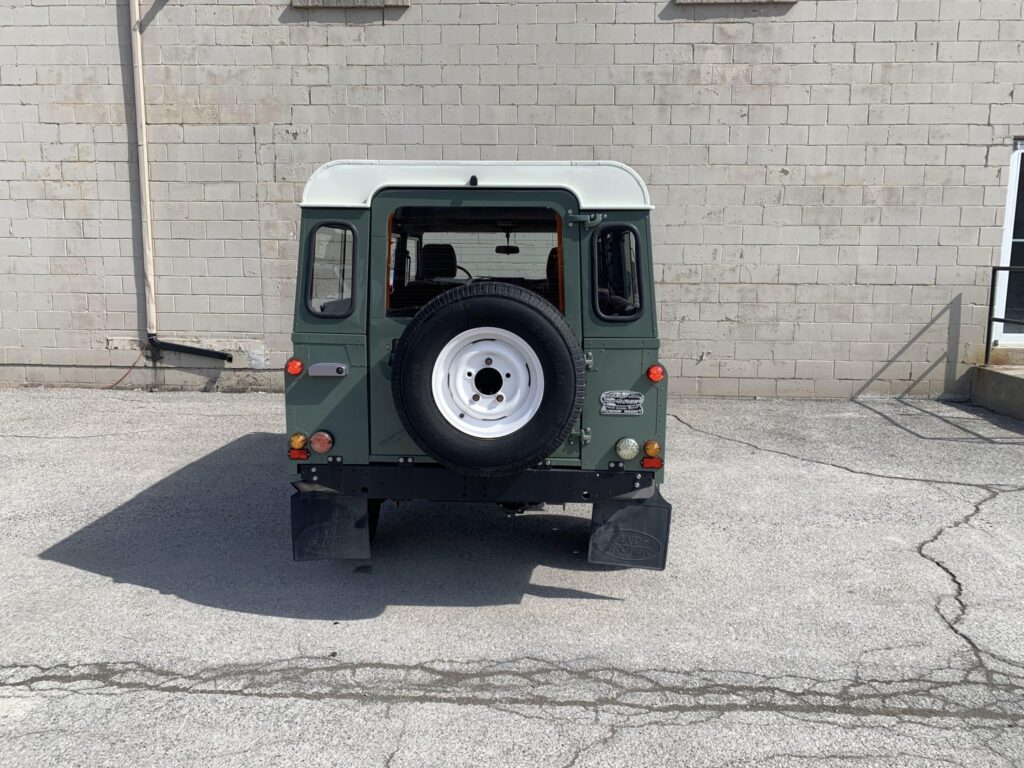 Rear view of The Nomad, a Keswick Green Defender 110 with a white spare wheel