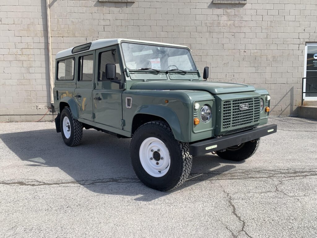 Front three-quarter view of The Nomad, a Keswick Green Defender 110 with white Wolf wheels