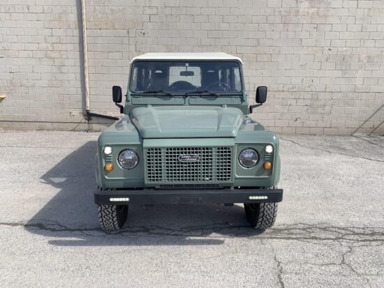 Head-on view of The Nomad, a Keswick Green Land Rover Defender 110 Station Wagon with a Chawton White roof