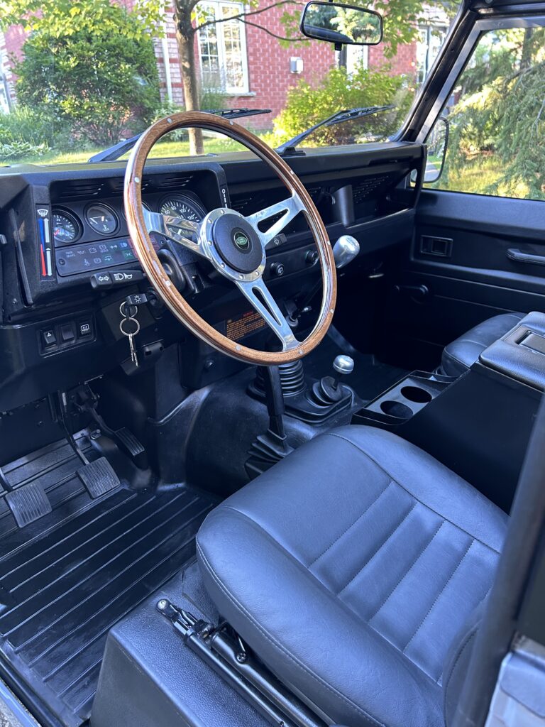 Wood steering wheel and black vinyl seats inside The Nazaré