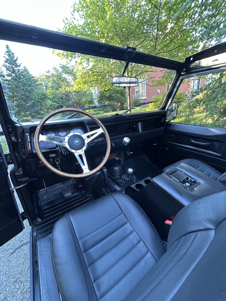 Driver's seat, wood steering wheel and dash of The Nazaré with the top down