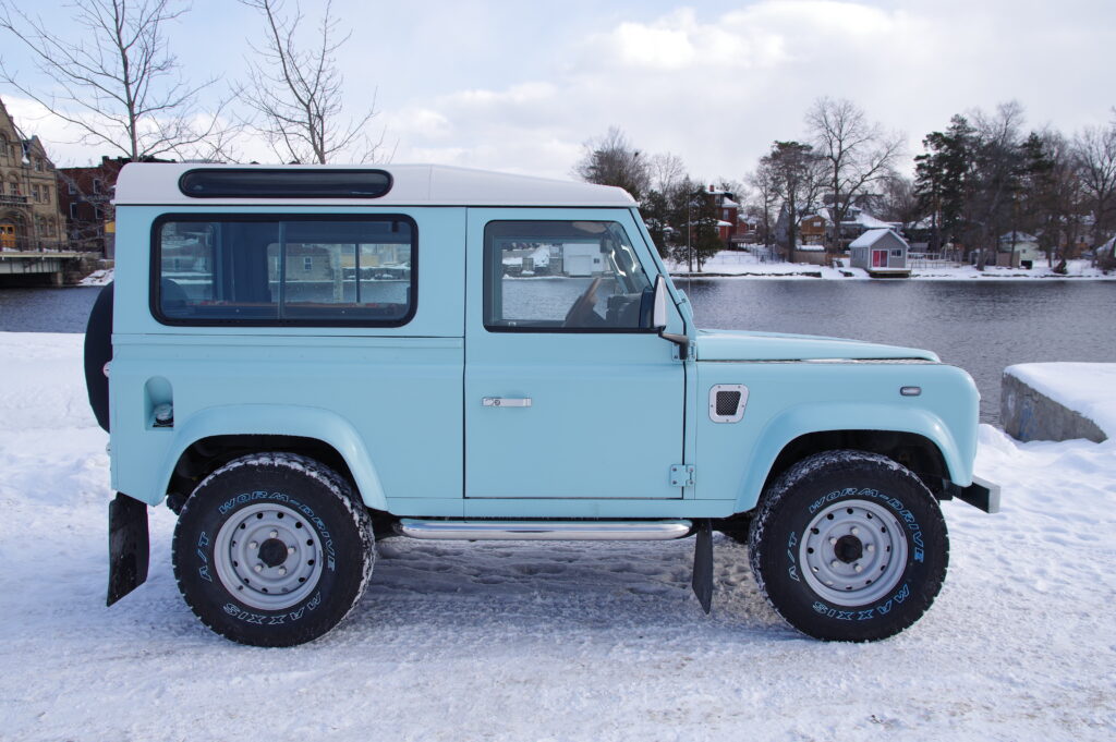 Side profile of Blue Crush, a matte Sonic Blue Defender 90 with an Alpine White roof and silver Wolf wheels
