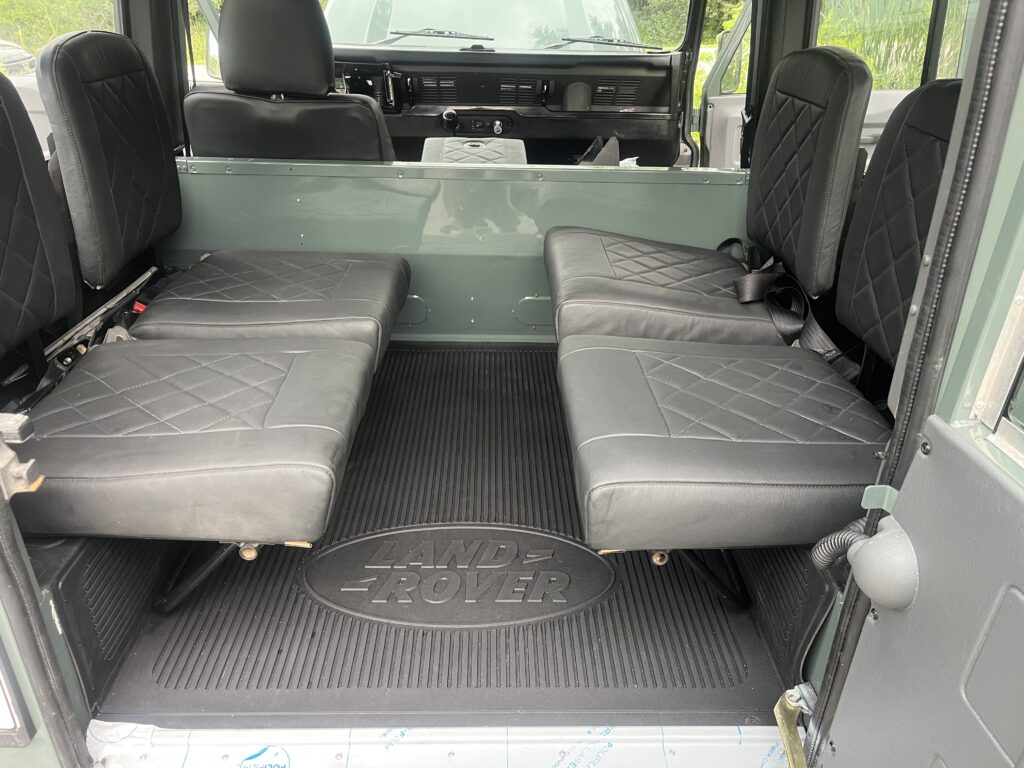 Rear load area of The Evergreen with black diamond-stitched leather tip-up seats