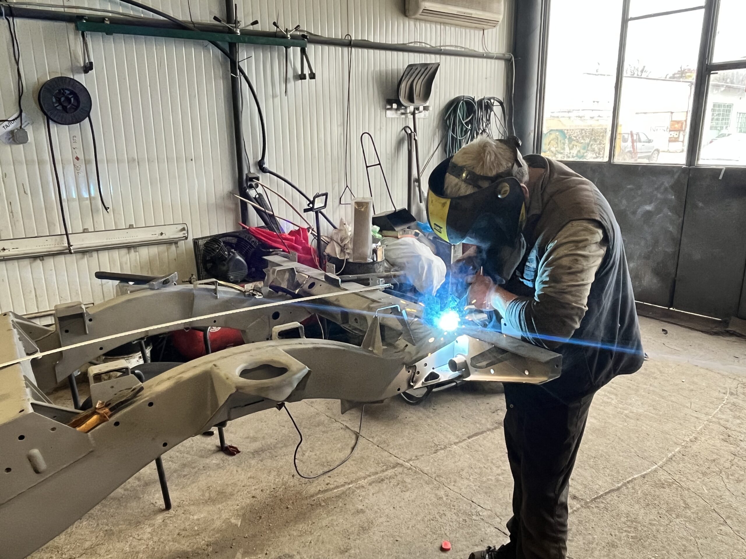 Welding the new heavy-duty rear crossmember onto the Ninety's original chassis at the factory position